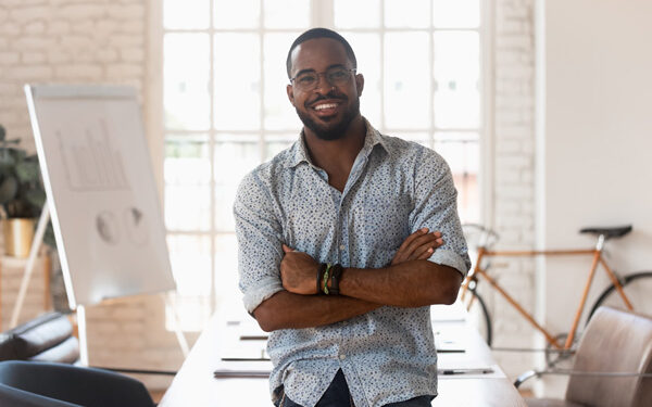 black man smiling arms folded desk in background bike leaning against wall