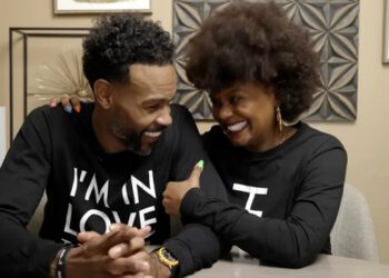 Tabitha Brown and husband wearing matching sweatshirts smiling