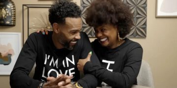 Tabitha Brown and husband wearing matching sweatshirts smiling