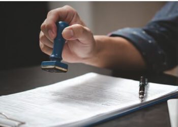 man with rubber stamp and papers on desk