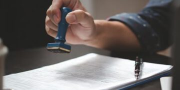 man with rubber stamp and papers on desk