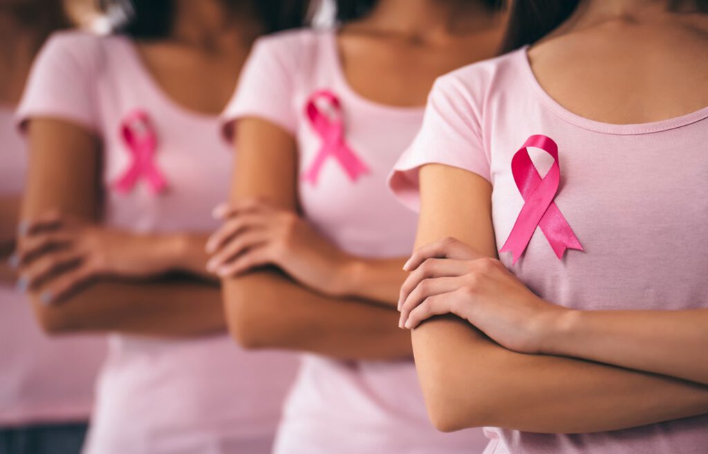 Cropped image of group of young multiracial woman with pink ribbons are struggling against breast cancer. Breast cancer awareness concept.