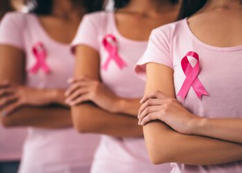 Cropped image of group of young multiracial woman with pink ribbons are struggling against breast cancer. Breast cancer awareness concept.