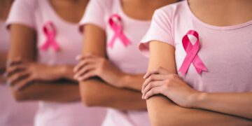 Cropped image of group of young multiracial woman with pink ribbons are struggling against breast cancer. Breast cancer awareness concept.