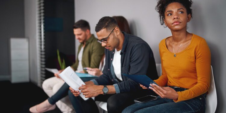 young african american woman feeling stressed about tedious waiting sitting in queue with other candidates for job interview