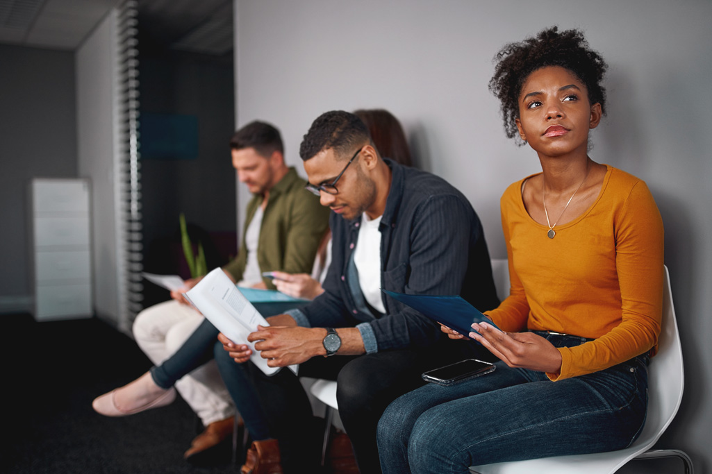 young african american woman feeling stressed about tedious waiting sitting in queue with other candidates for job interview