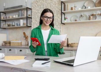 Young latina female work from home in kitchen with laptop