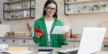 Young latina female work from home in kitchen with laptop