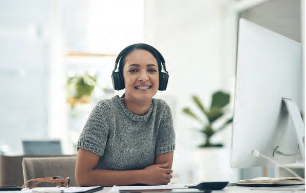 young woman at work with headphones on and smiling