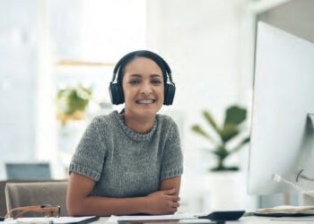 young woman at work with headphones on and smiling