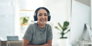 young woman at work with headphones on and smiling