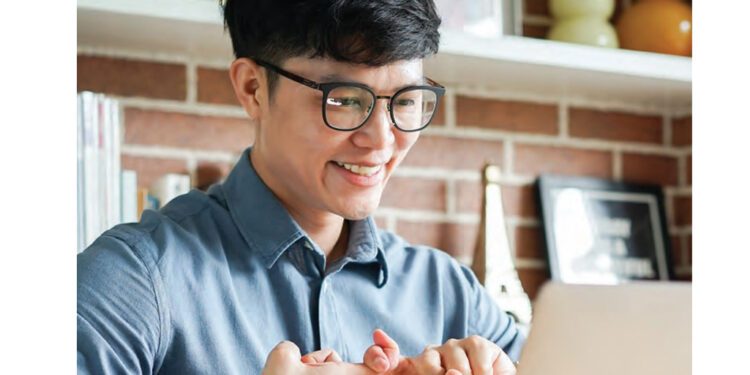 man looking at monitor with fingers crossed