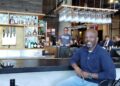 Rustik Taverns Owner Frantz Metellus Poses In Front Of The Restaurants Bar. Photo Credit_ Karen Juan.jpeg